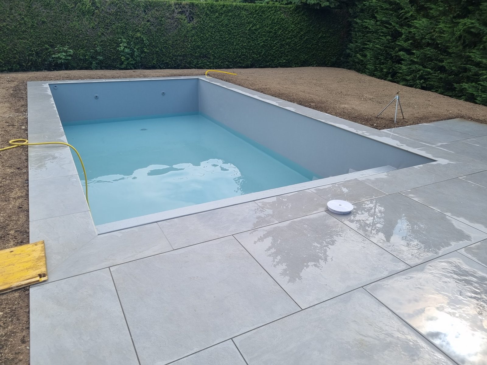 Piscine en eau avec margelles et terrasse en dalles grises, liner gris clair