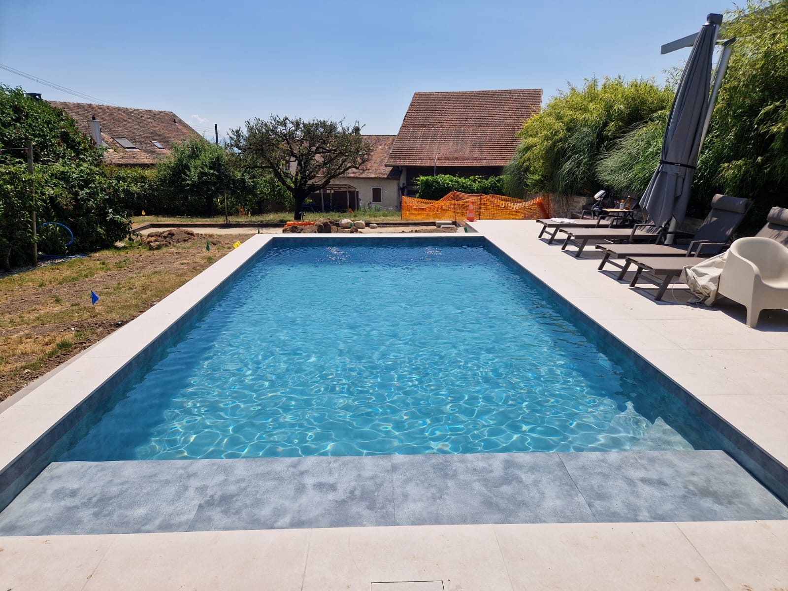 Vue frontale de la piscine PVC 3D, eau turquoise scintillante et plage immergée grise