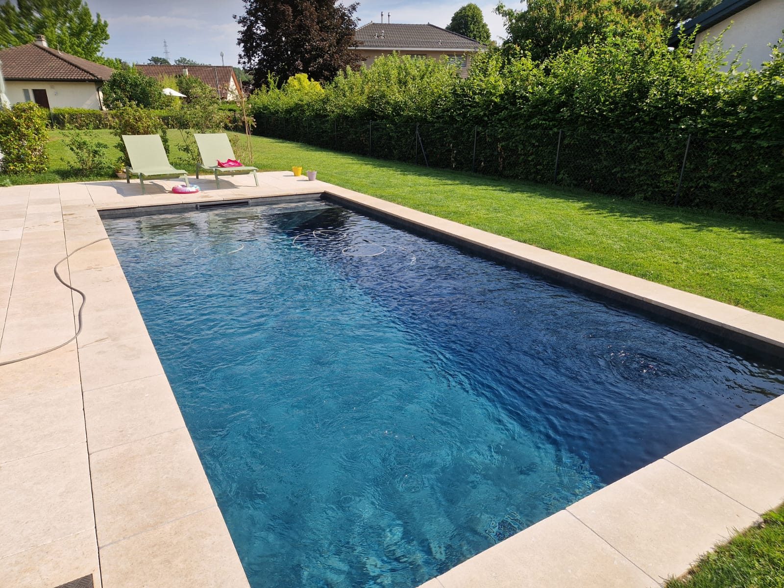 Piscine béton habillée de PVC 3D foncé, eau bleu profond aux reflets moirés, margelles en pierre claire