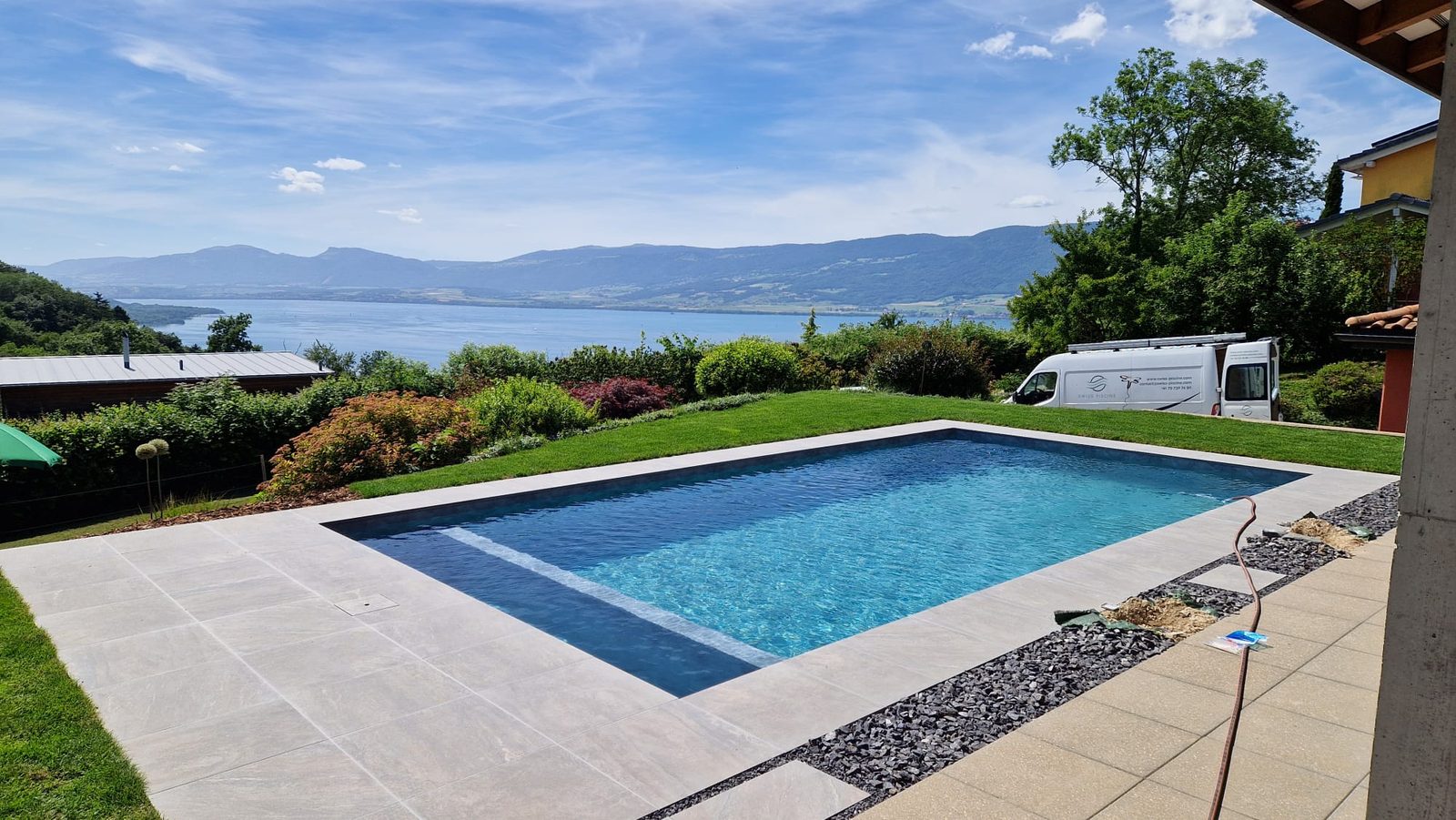 Piscine béton à l'eau turquoise avec vue panoramique sur le lac de Neuchâtel
