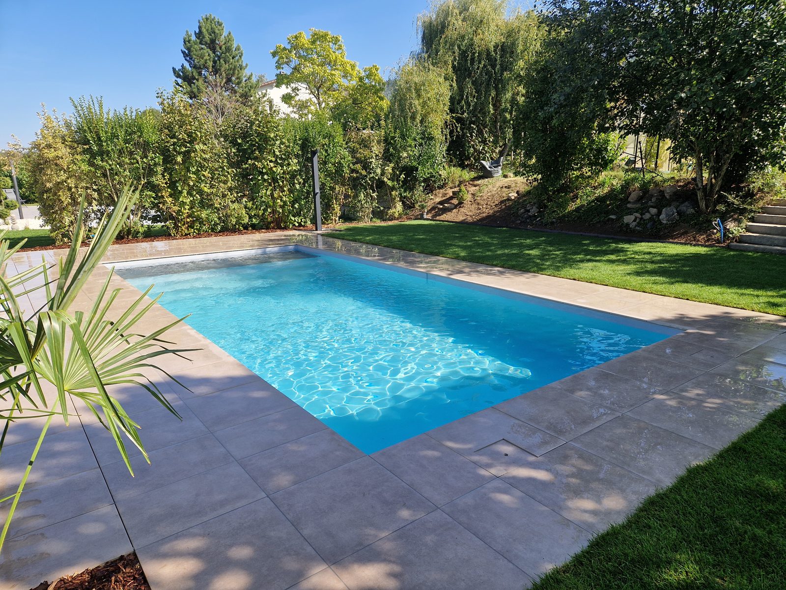Swiss Piscine project: AKOYA fibreglass pool in azure blue with a tiled deck in Yvonand