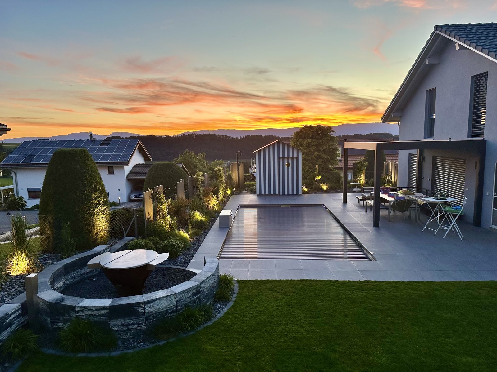 Sunset panorama over the stainless-steel pool, pergola and fire pit