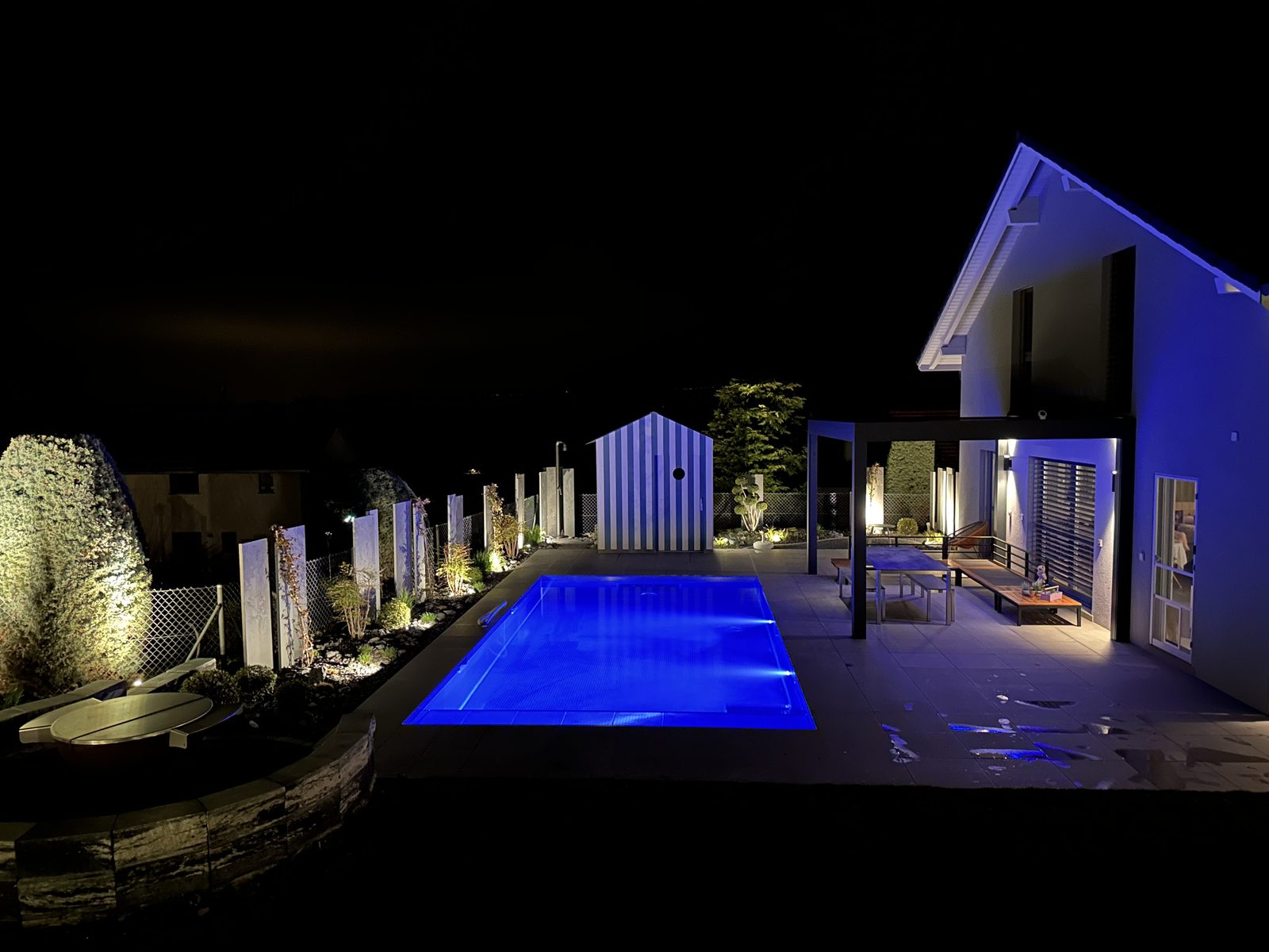 Stainless-steel pool lit up in blue at night in front of the villa