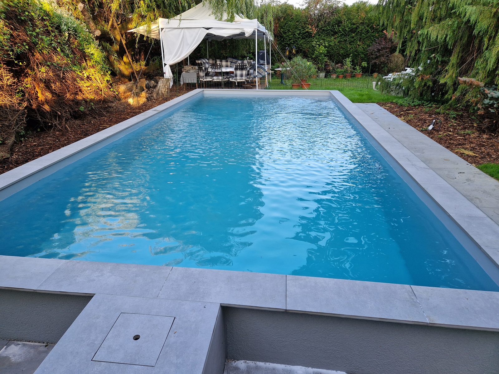 Piscine rénovée en PVC armé gris clair, eau turquoise limpide vue en enfilade