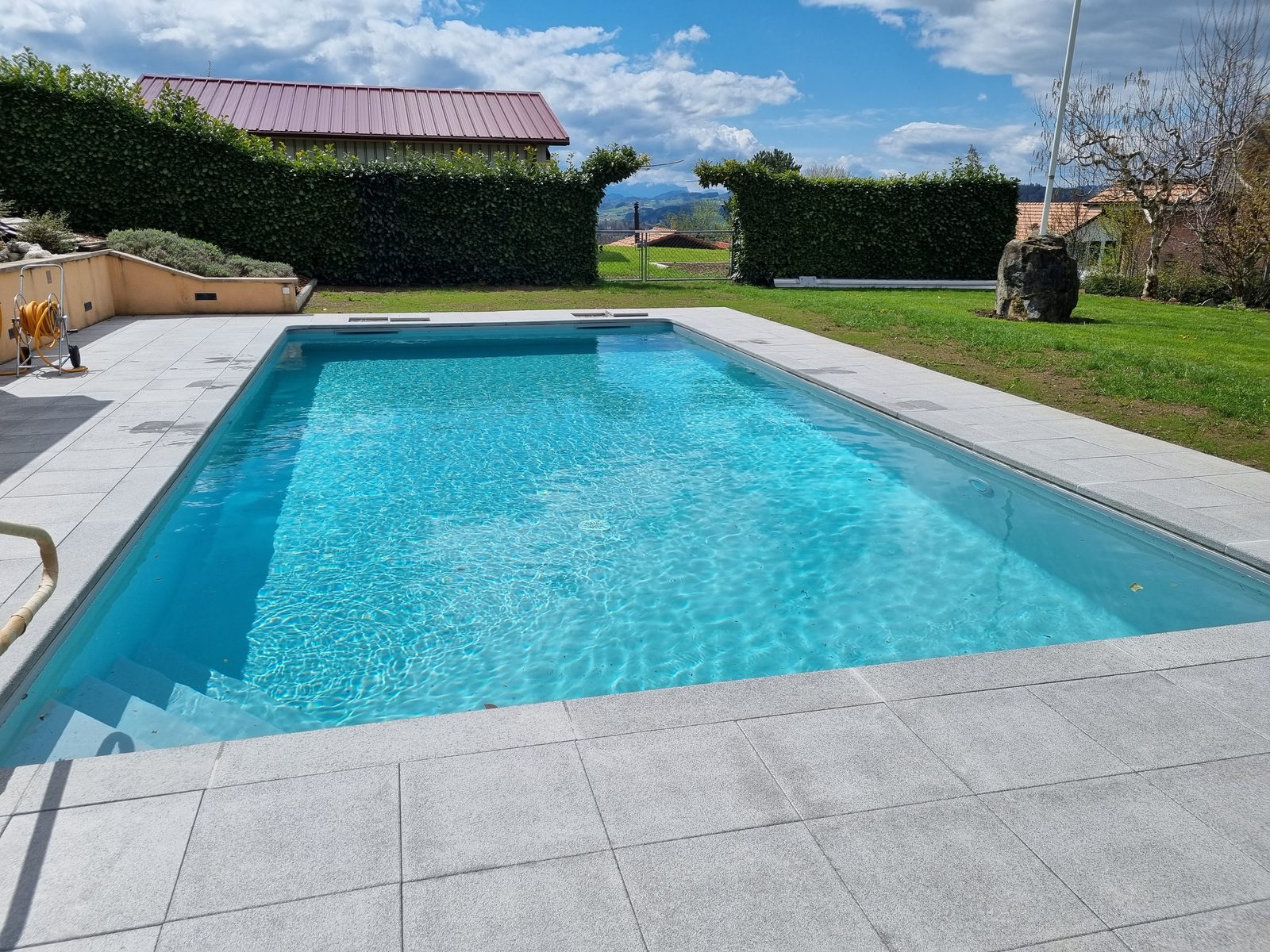 Piscine rénovée en PVC armé gris, eau turquoise étincelante, plage en dalles granit