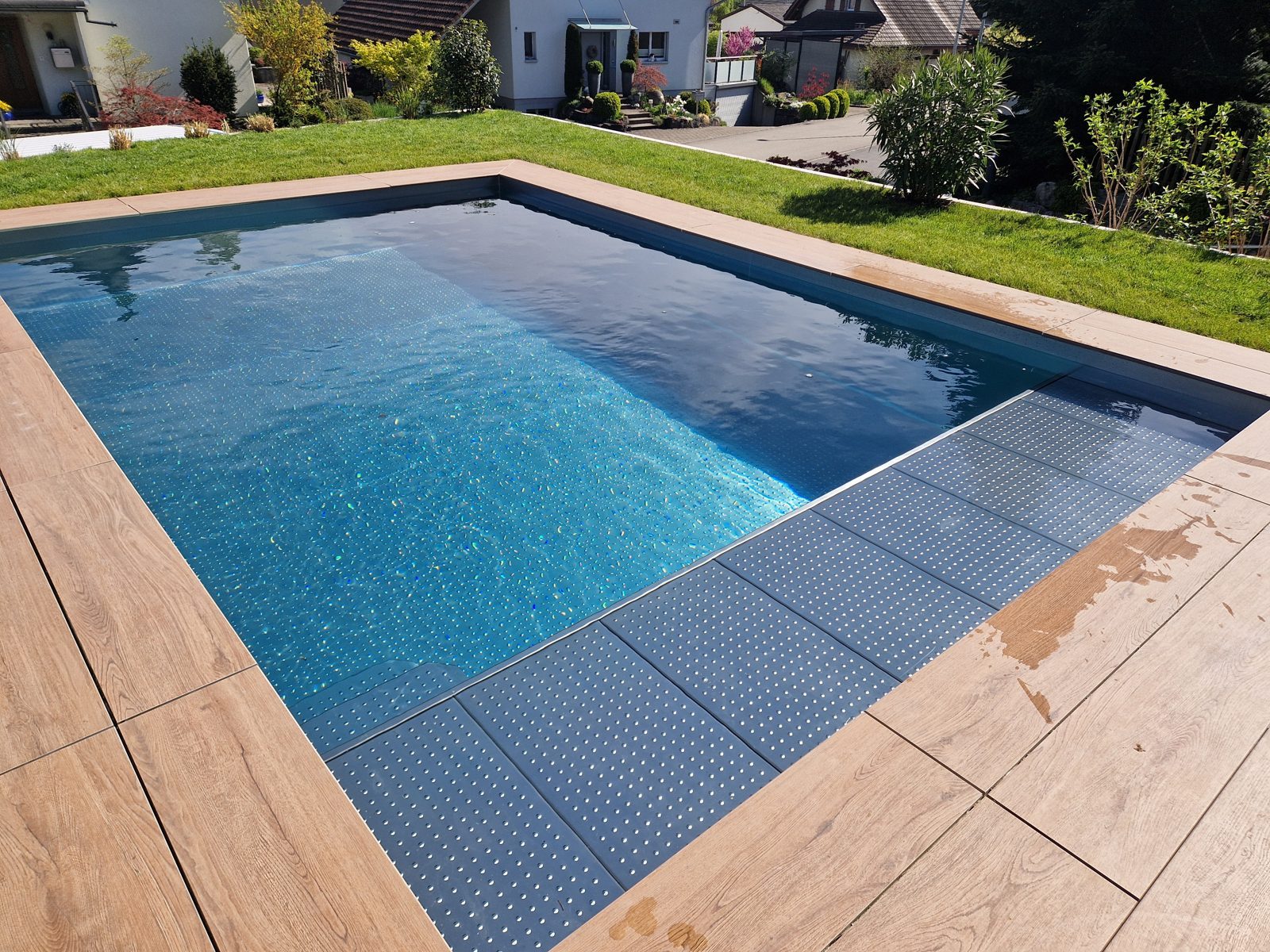 Stainless-steel pool with shifting reflections, stone terrace